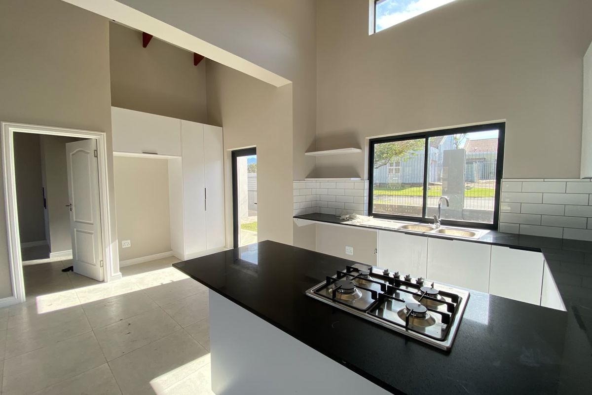 Modern kitchen featuring a gas hob, stone countertops, subway tile backsplash, and high ceilings, offering a bright and spacious layout.