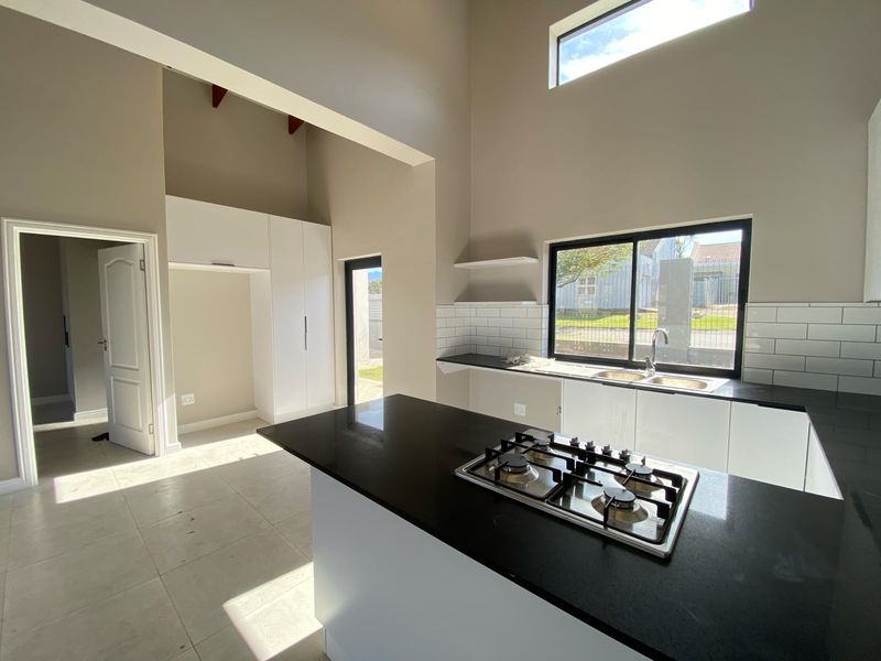 Modern kitchen featuring a gas hob, stone countertops, subway tile backsplash, and high ceilings, offering a bright and spacious layout.