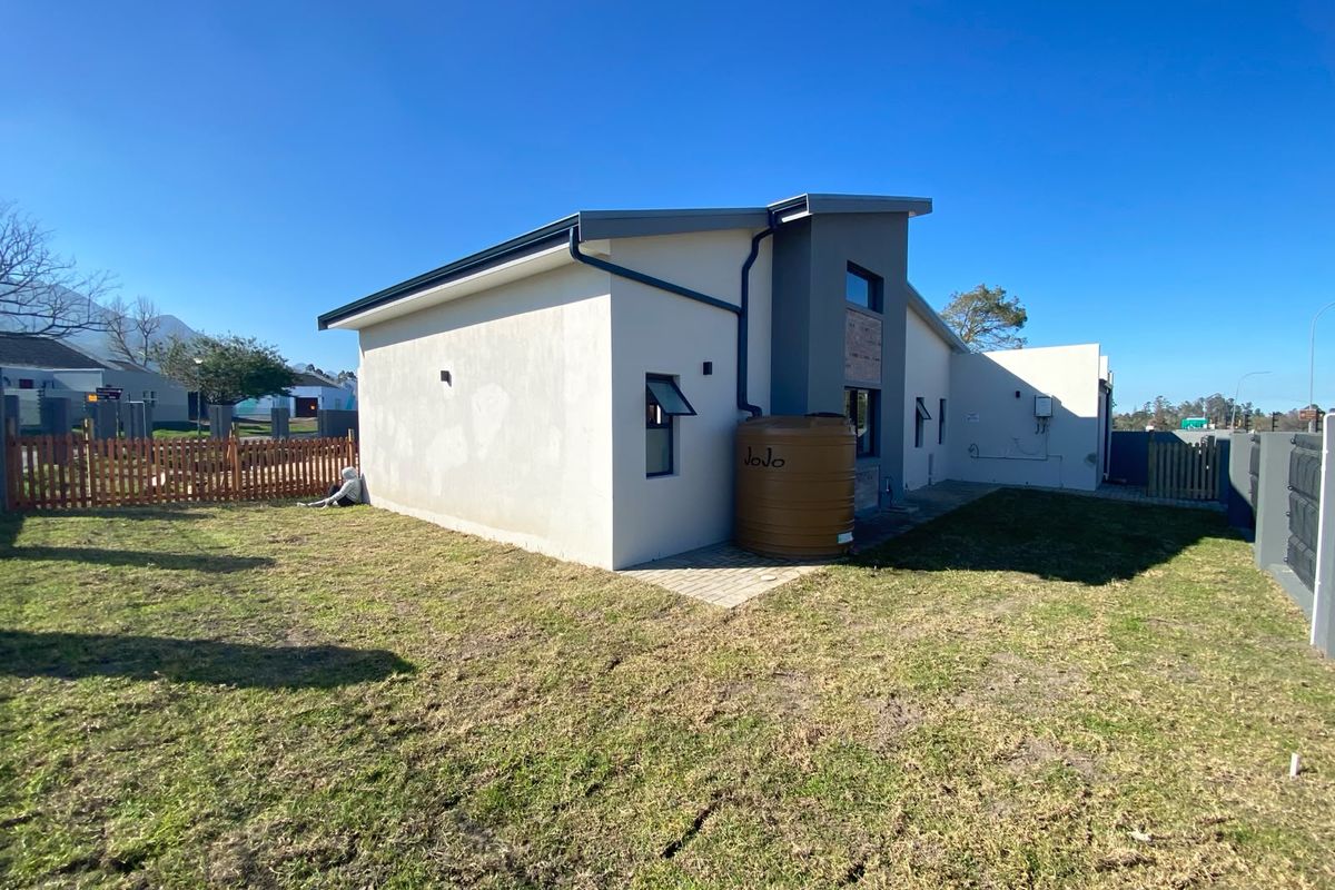 Rear view of the property featuring a modern facade, a water storage tank, and a private garden area with timber fencing.