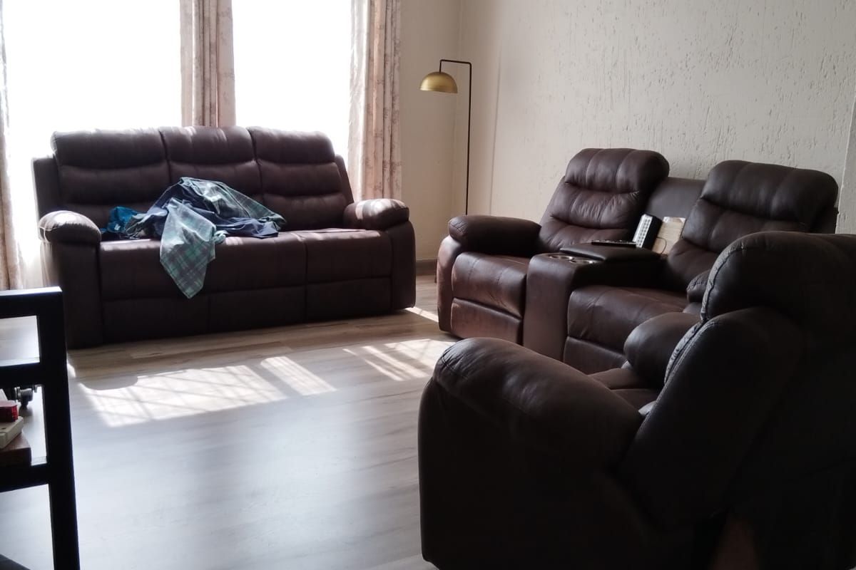 A bright living room featuring laminate wood flooring and textured wall finishes, illuminated by natural light from large windows.