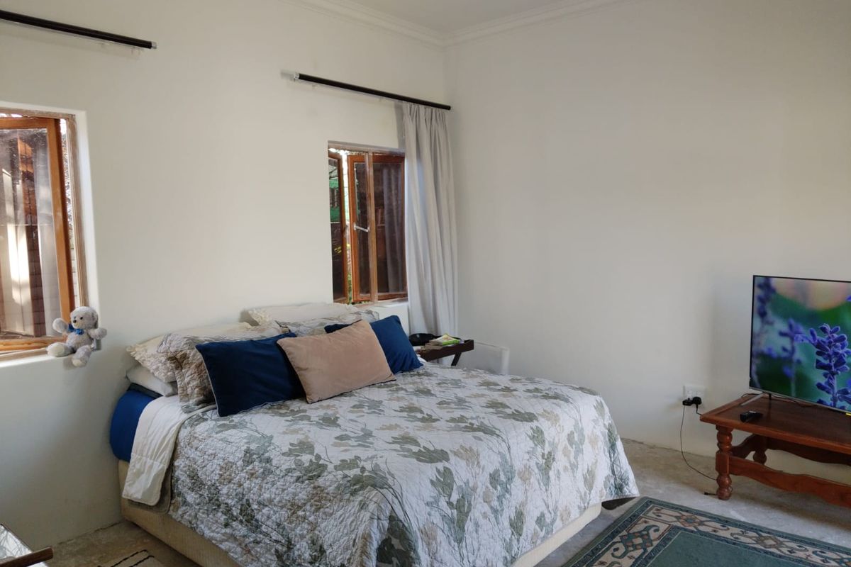 A bedroom featuring timber-framed windows, crown molding, and neutral walls, providing a functional and comfortable sleeping space.
