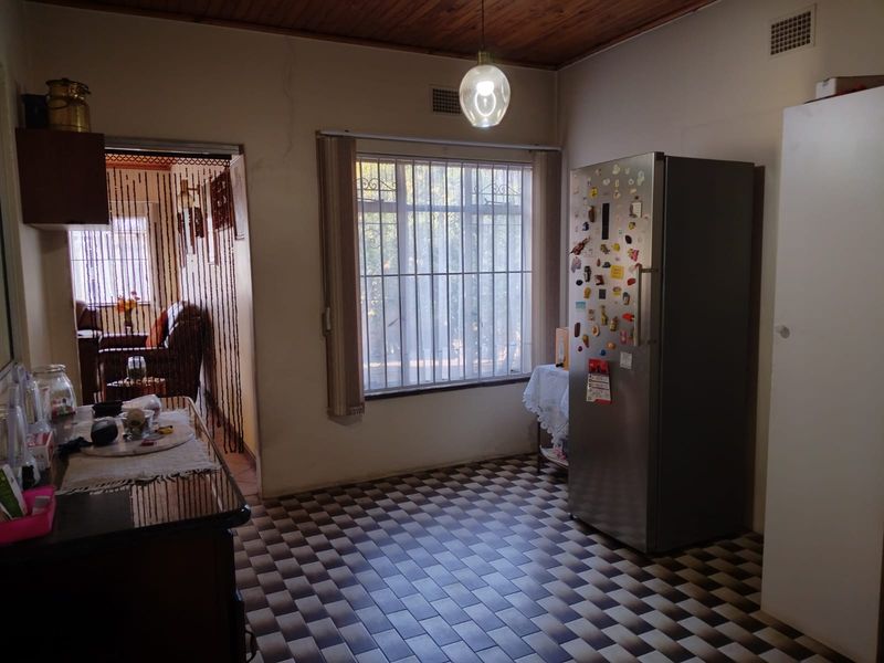 A kitchen area featuring timber ceilings, tiled flooring, and security bars on the window, offering a functional space with potential for cosmetic updates.