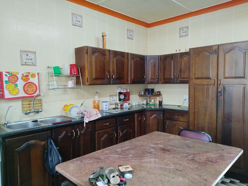 A functional kitchen featuring traditional wooden cabinetry, granite countertops, and a double bowl stainless steel sink with a tiled backsplash.