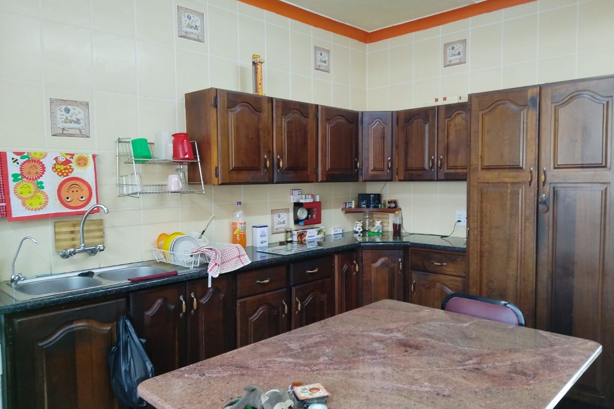 A functional kitchen featuring traditional wooden cabinetry, granite countertops, and a double bowl stainless steel sink with a tiled backsplash.