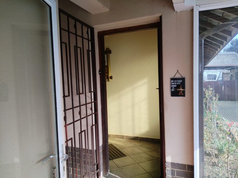 An entrance area featuring a security gate, tiled flooring, and a timber door frame leading into the interior of the home.