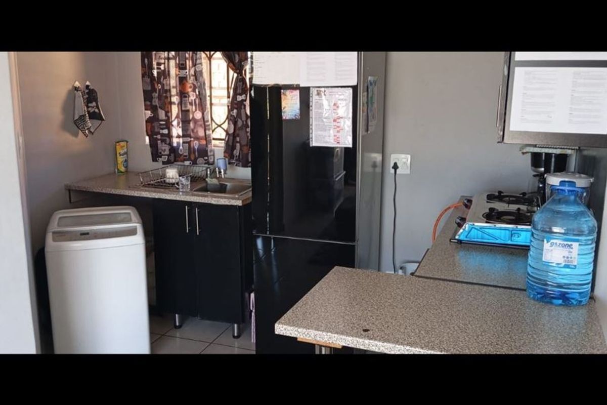 Compact kitchen area featuring built-in cabinetry, a stainless steel sink, and a gas hob, providing functional space for daily meal preparation.