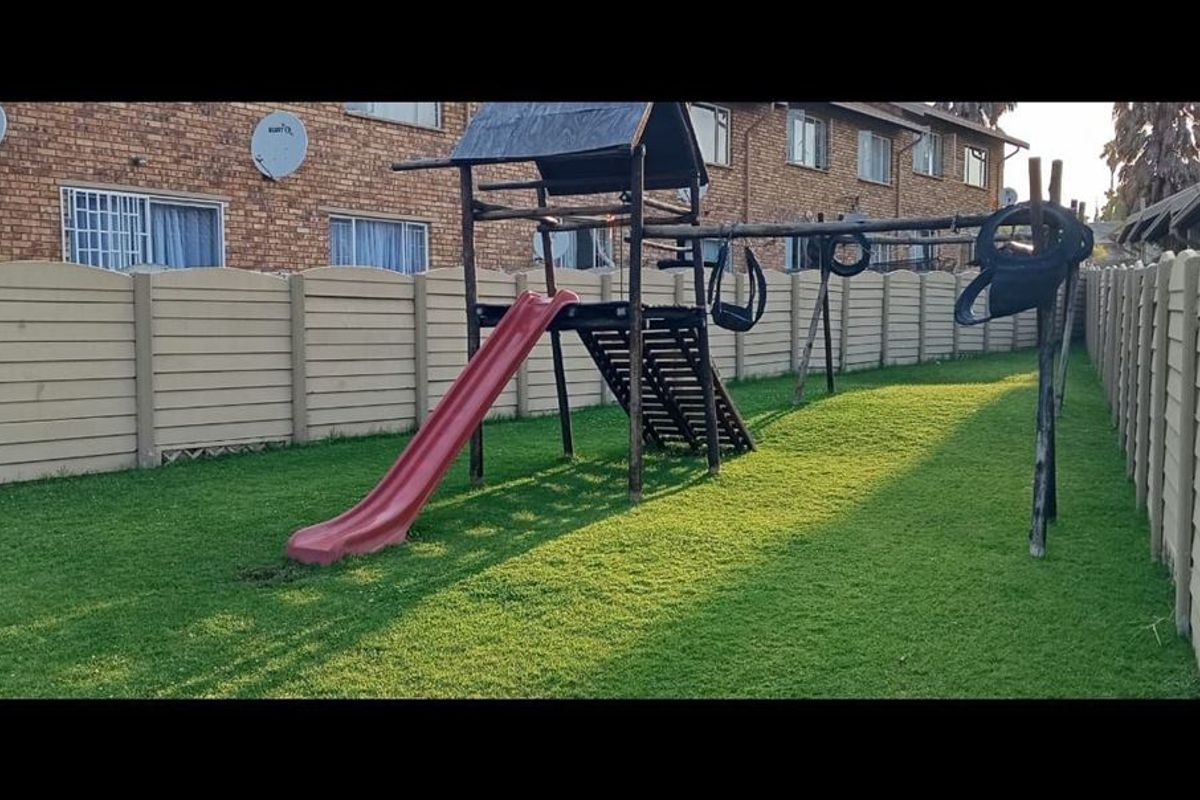 A private rear garden area featuring a well-maintained lawn and a precast concrete boundary wall, providing a secure outdoor space for the townhouse.