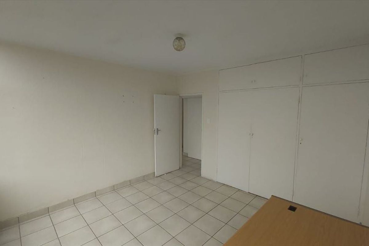 A vacant bedroom featuring tiled flooring and built-in storage cupboards with overhead compartments.
