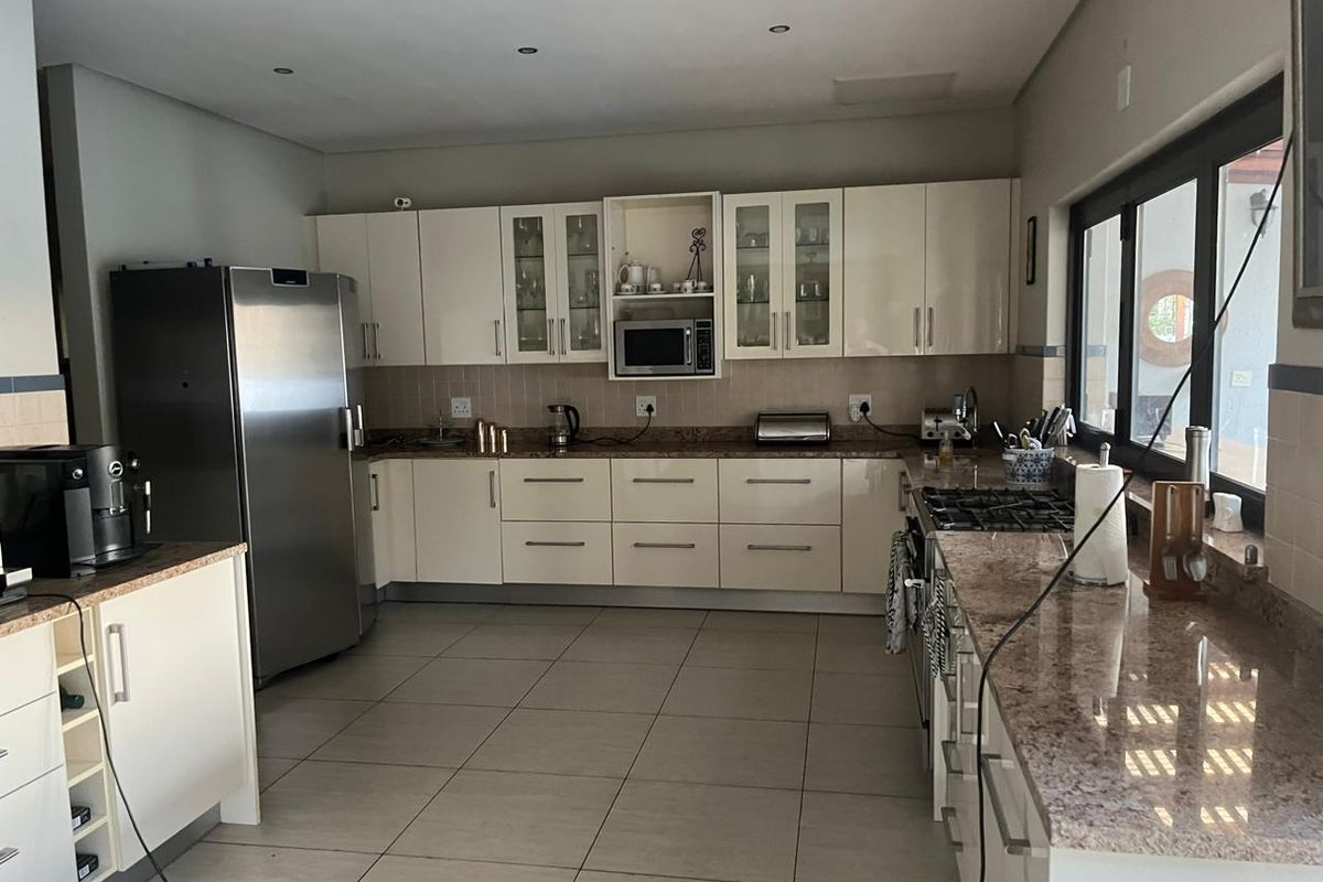A functional kitchen featuring cream cabinetry, granite countertops, tiled flooring, and built-in appliances including a gas hob and microwave.