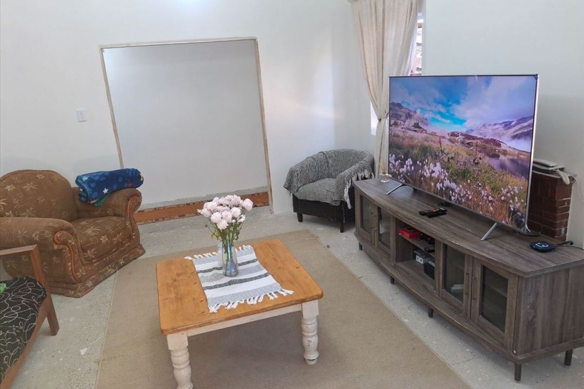 A living room space featuring an unfinished wall opening and exposed flooring, offering potential for renovation and customization.