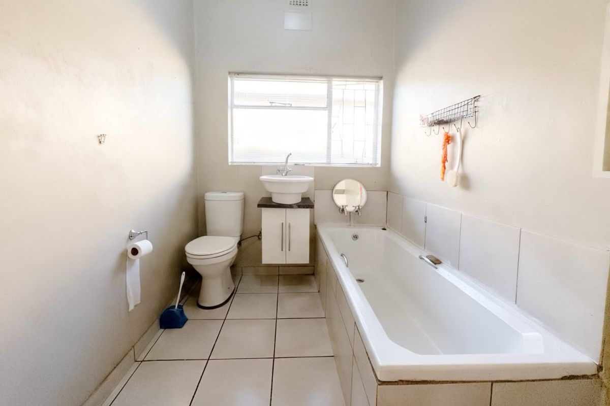 A functional bathroom featuring a built-in bathtub, a wall-mounted vanity with a basin, and a standard toilet.