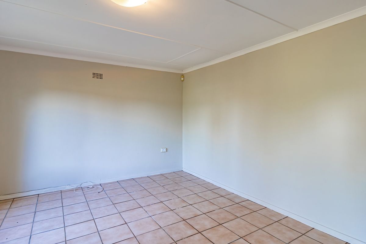 A vacant bedroom featuring neutral painted walls, tiled flooring, and a standard ceiling light fixture.