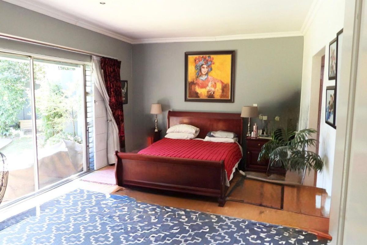Spacious bedroom featuring large sliding glass doors providing direct access to the garden, recessed ceiling lighting, and neutral wall finishes.