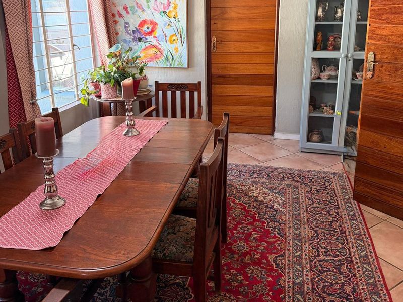 A dining room featuring tiled flooring, a wooden door, and a window with security bars, providing a functional space for family meals.