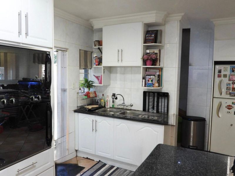 A functional kitchen featuring white cabinetry, granite countertops, a double-basin sink, and a built-in eye-level oven.