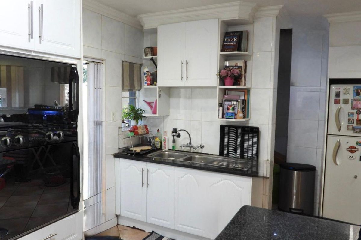 A functional kitchen featuring white cabinetry, granite countertops, a double-basin sink, and a built-in eye-level oven.