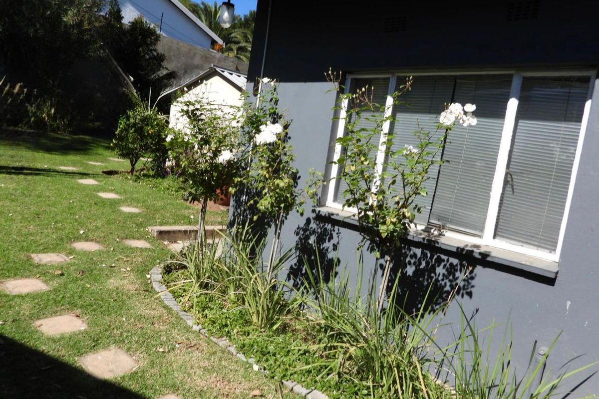 A view of the rear exterior of the house featuring a landscaped garden area with a paved walkway and established garden beds.