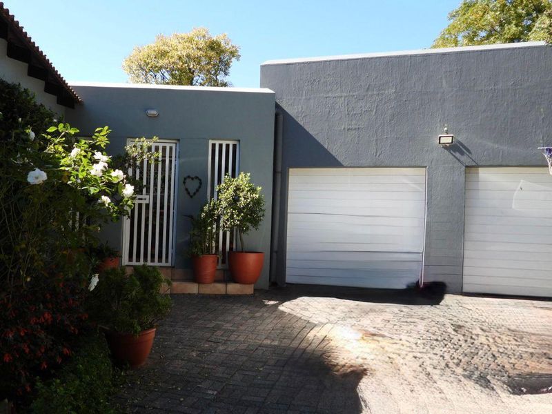 A view of the property exterior featuring a paved driveway, a double garage with white sectional doors, and a secure side entrance.