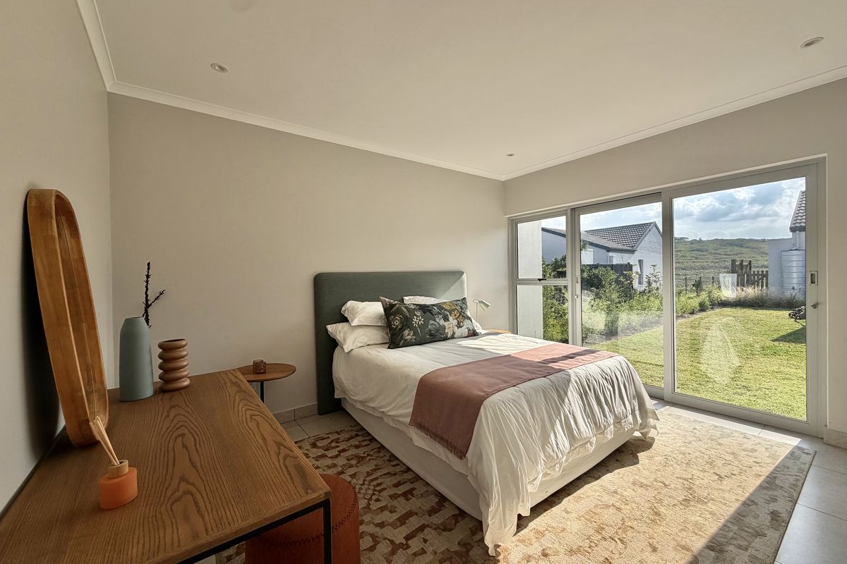 A bright bedroom featuring large sliding glass doors that provide direct access to the garden and allow for ample natural light.
