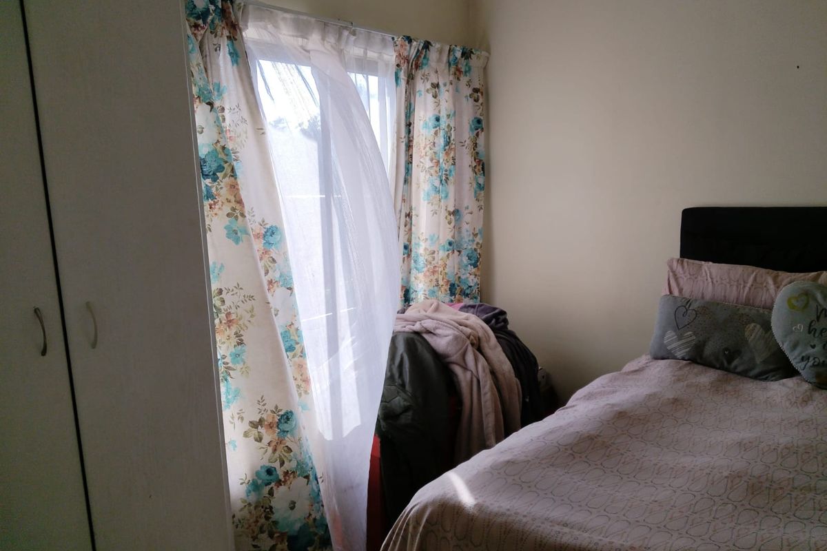 A bedroom featuring built-in cupboards and a window with natural light.