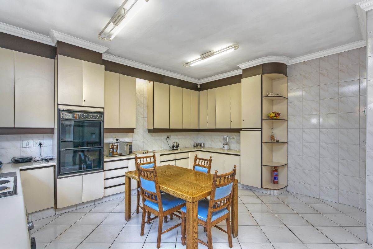 A functional kitchen featuring built-in cabinetry, integrated oven, and tiled flooring, offering a practical layout with ample storage space.