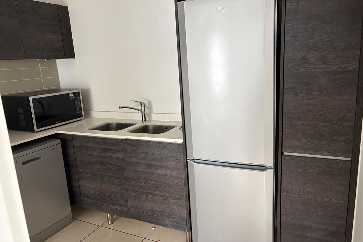 Modern kitchen featuring dark wood grain cabinetry, stone countertops, a double stainless steel sink, and tiled flooring in a clean, contemporary layout.