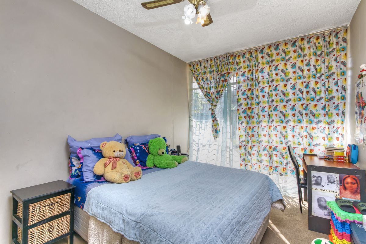 A bedroom featuring carpeted flooring, a ceiling fan, and large windows with natural light access.