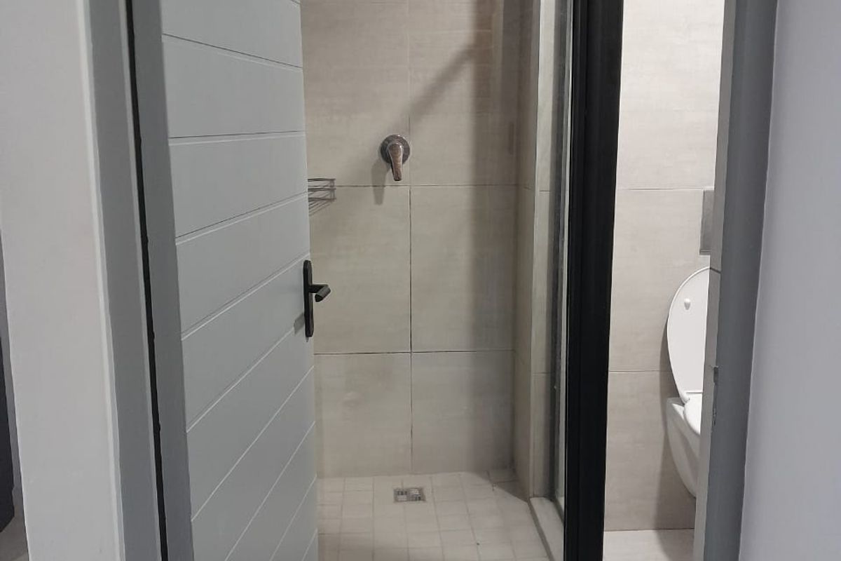 A modern bathroom featuring a walk-in shower with a black frame, tiled walls, and a wall-mounted toilet.