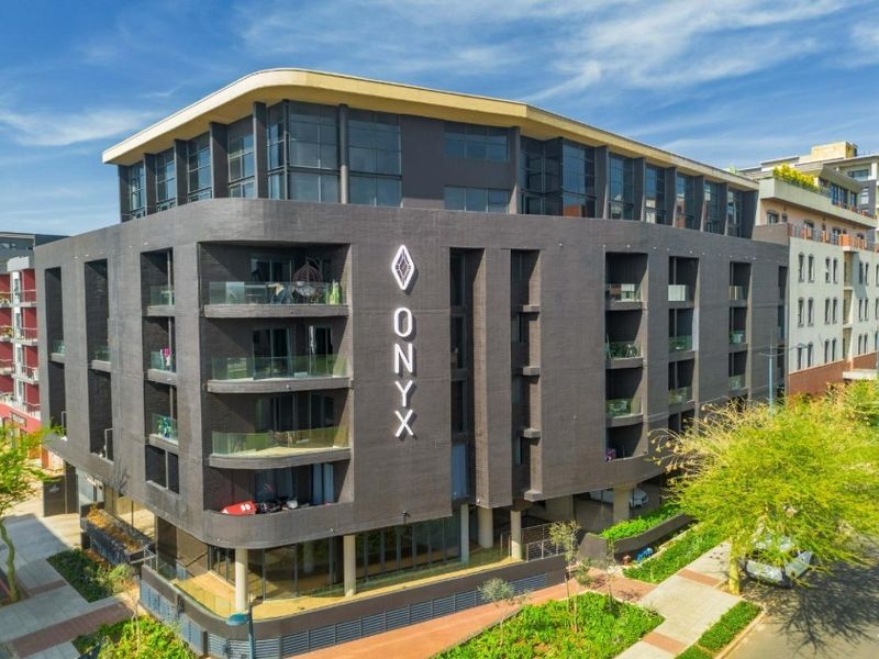 Aerial view of The Onyx apartment building, showcasing its modern dark facade, glass balconies, and prominent architectural signage.