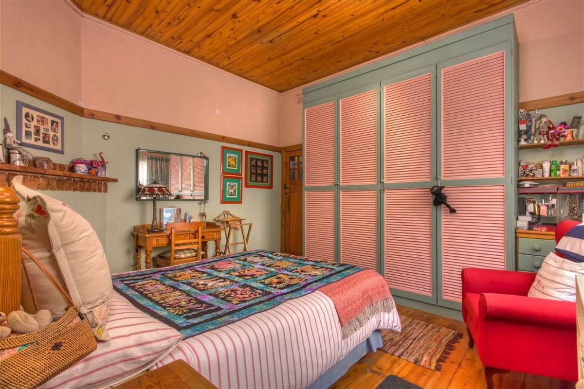 A bedroom featuring a timber-paneled ceiling, built-in louvered wardrobes, and original wooden flooring, offering a classic and character-filled living space.