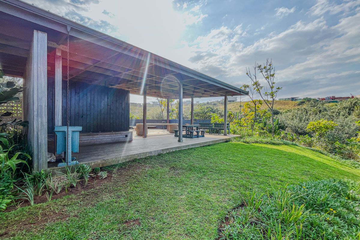 A spacious covered timber deck patio overlooking a landscaped garden and natural surroundings, providing an ideal outdoor entertainment area.