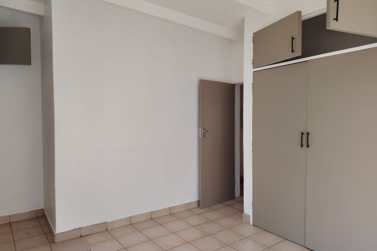 An empty bedroom featuring tiled flooring and built-in cupboards with modern hardware, offering a blank canvas for personalization.