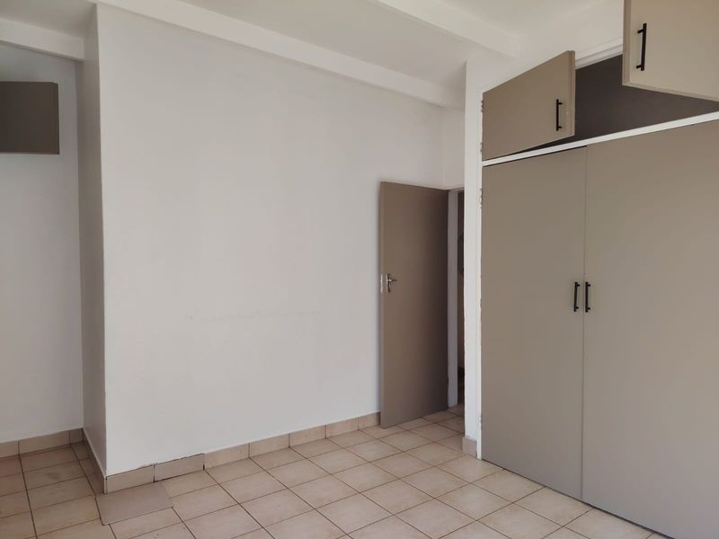 An empty bedroom featuring tiled flooring and built-in cupboards with modern hardware, offering a blank canvas for personalization.