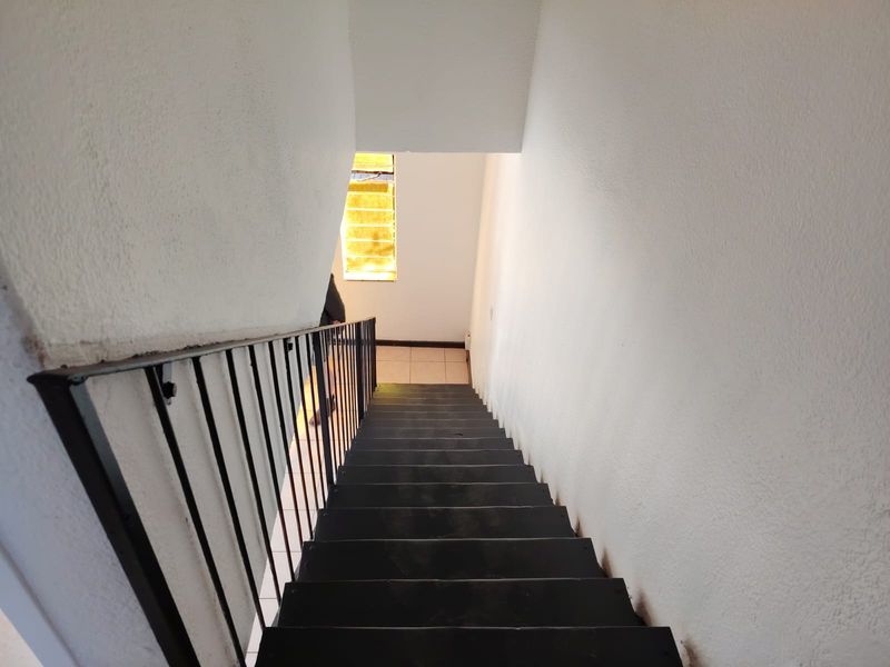 A functional interior staircase featuring a metal balustrade and tiled landing area, providing access between levels of the townhouse.