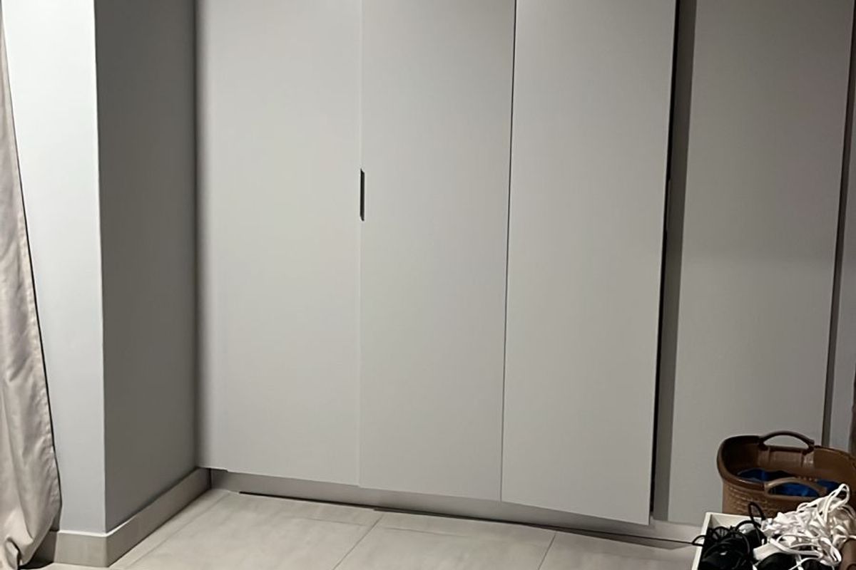 A bedroom featuring built-in floor-to-ceiling cabinetry with a clean, modern finish and neutral tiled flooring.