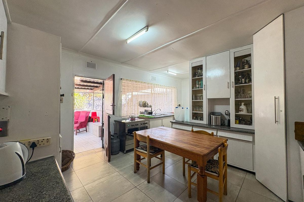 A functional kitchen featuring tiled flooring, built-in white cabinetry with glass display sections, and direct access to an outdoor patio area.