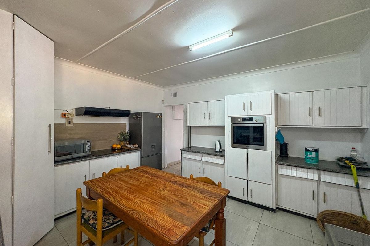 A functional kitchen featuring white built-in cabinetry, laminate countertops, a built-in oven, and an extractor fan, with tiled flooring throughout.