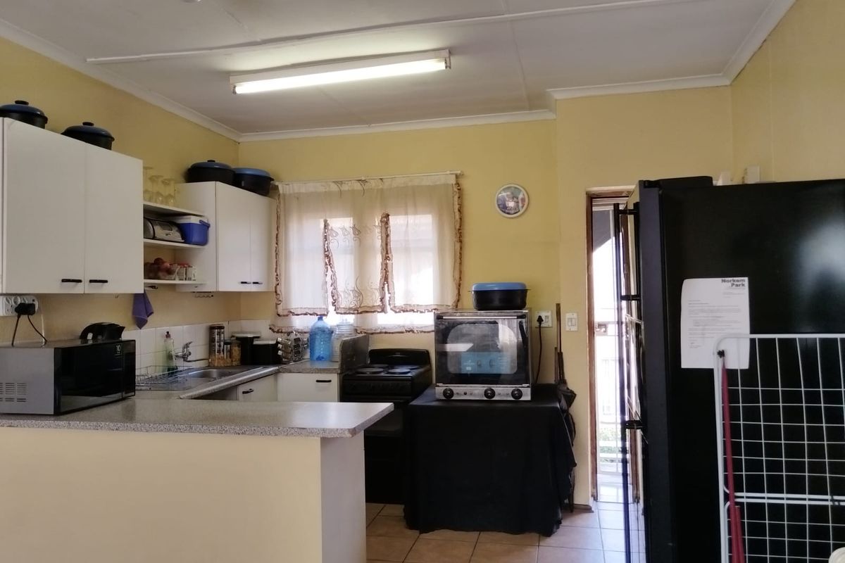 A functional kitchen featuring built-in cabinetry, laminate countertops, and a tiled floor, offering a practical layout for daily meal preparation.