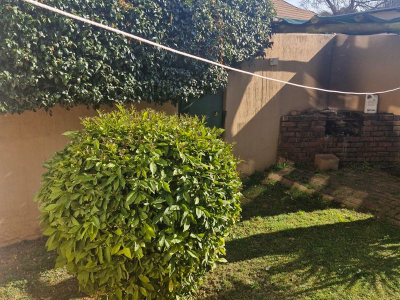 A private rear garden area featuring a brick built-in braai, established perimeter hedging, and a lawn space.
