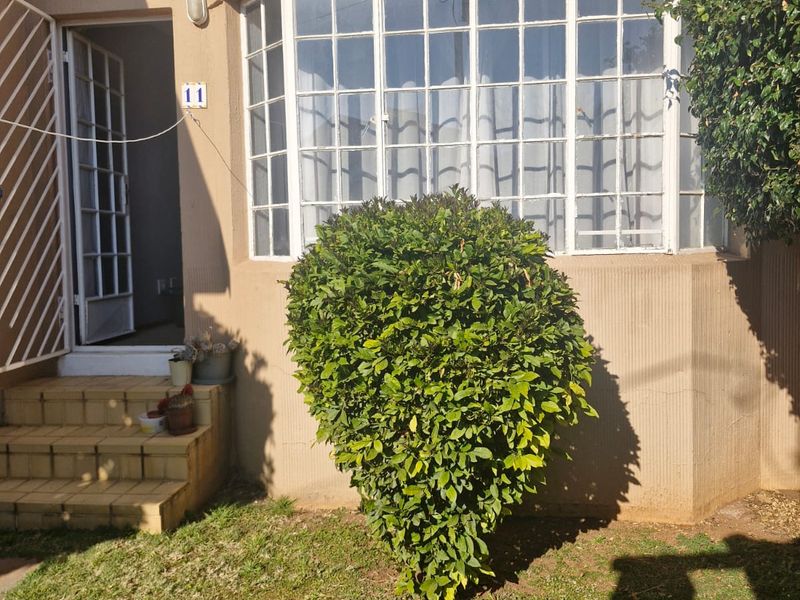 Front entrance of the apartment featuring a bay window, security gate, and tiled steps leading to the main door.