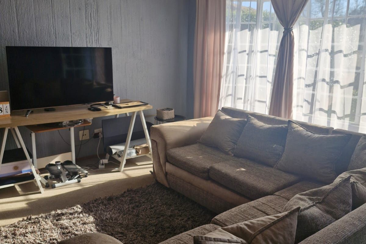 A comfortable living room featuring a ceiling fan, textured wall finishes, and large windows that provide ample natural light.