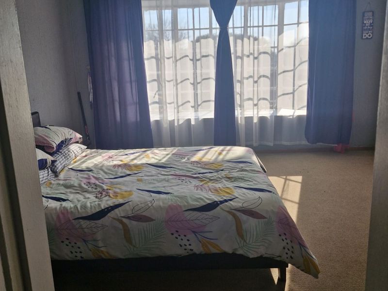 A bedroom featuring carpeted flooring and a large window with natural light, providing a functional space for rest.
