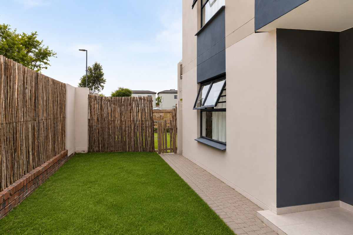 A private rear garden area featuring a manicured lawn, paved walkway, and natural timber fencing, providing a clean and well-maintained outdoor space.