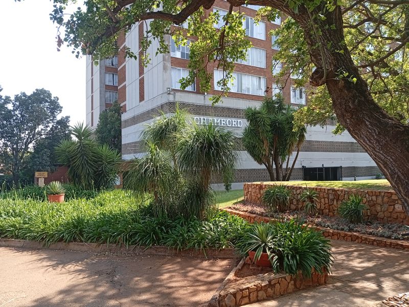 Exterior view of the Chambord apartment building featuring a brick facade, decorative concrete detailing, and landscaped stone retaining walls.