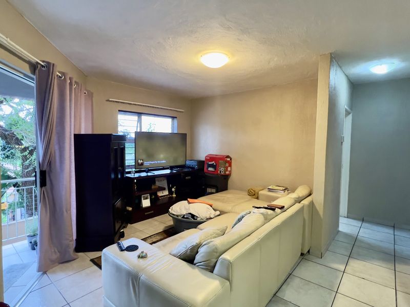 A living room area featuring tiled flooring and a sliding glass door leading to an outdoor balcony space.