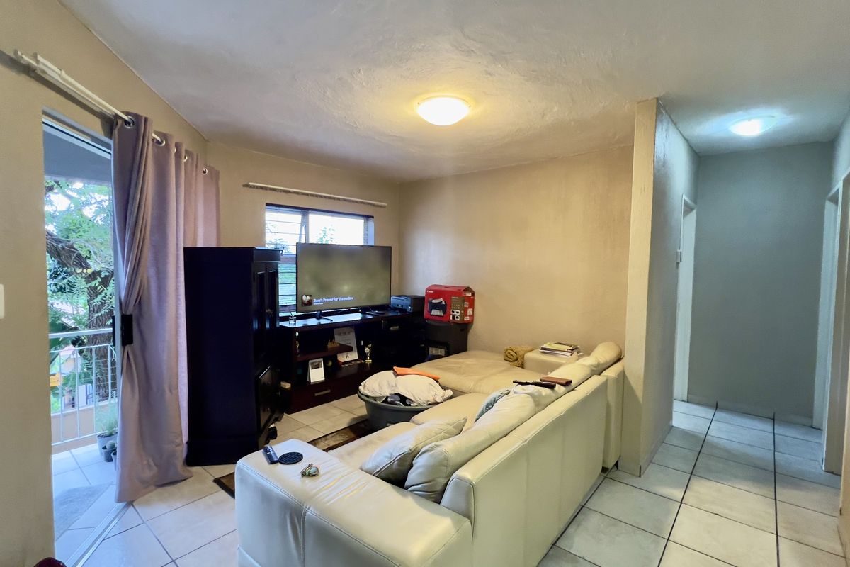 A living room area featuring tiled flooring and a sliding glass door leading to an outdoor balcony space.