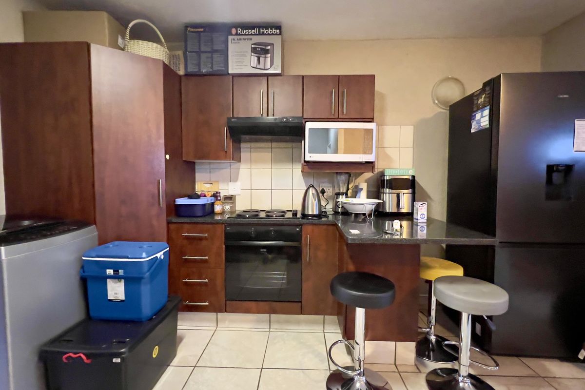 Compact kitchen featuring dark wood cabinetry, built-in oven and hob, tiled backsplash, and a breakfast counter with seating area.