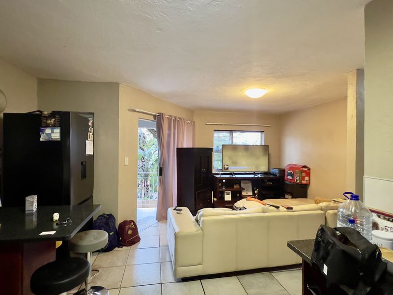Open-plan living area featuring a kitchen with granite countertops and tiled flooring, with direct access to an outdoor balcony through a sliding glass door.
