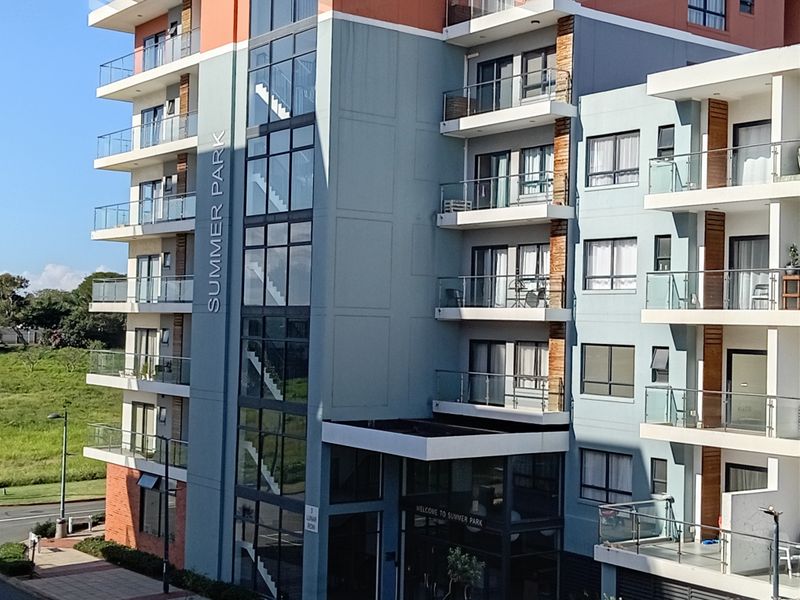 Exterior view of the Summer Park apartment complex, featuring modern multi-story architecture with glass balconies and a prominent stairwell facade.