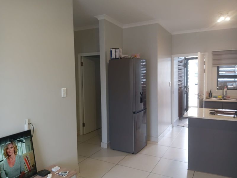 An open-plan living and kitchen area featuring tiled flooring, neutral wall tones, and direct access to an exterior doorway.